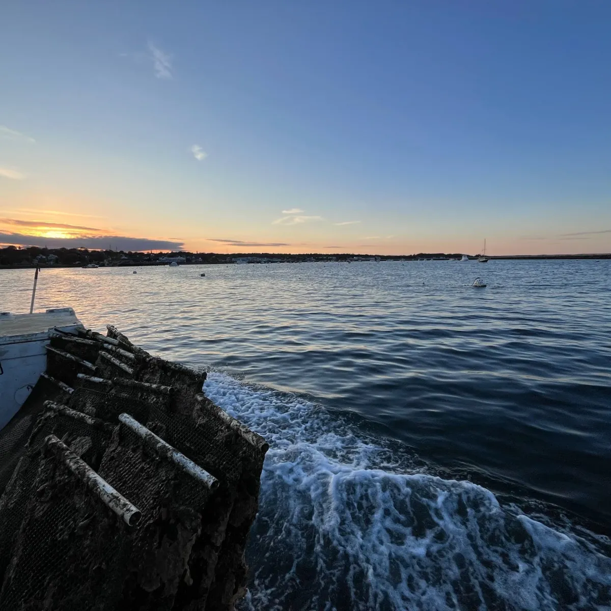 Sunset over a calm sea with a pier in the foreground.