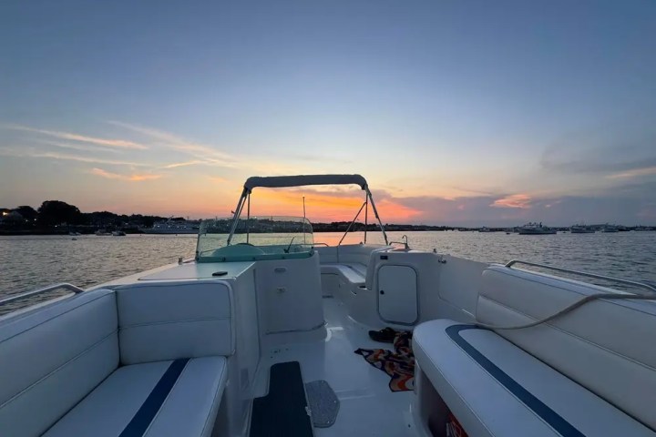 Boat interior facing sunset over calm water and distant shoreline.