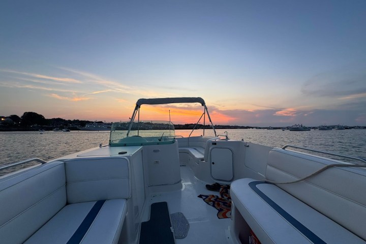 Boat on water at sunset with empty seating, clear sky in background.