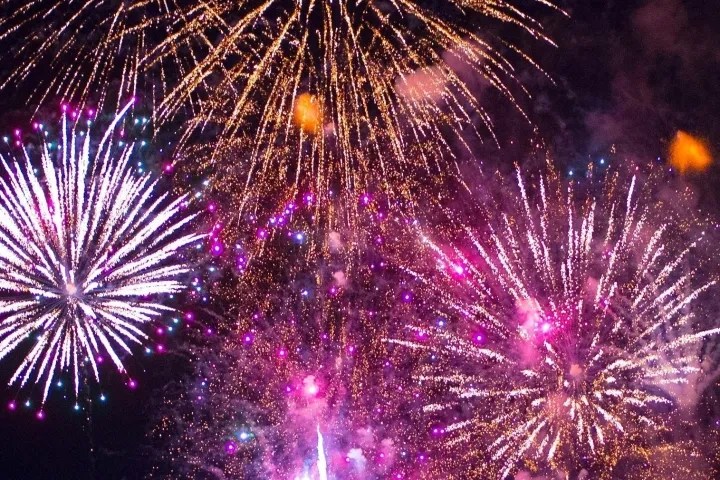 Colorful fireworks exploding in the night sky with bursts of pink, purple, and gold.